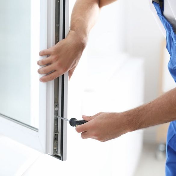 Handwerker schraubt an einem Fenster